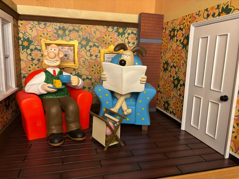 Painted Wallace and Gromit diorama: Wallace in a red armchair with cheese and tea, Gromit reading a newspaper